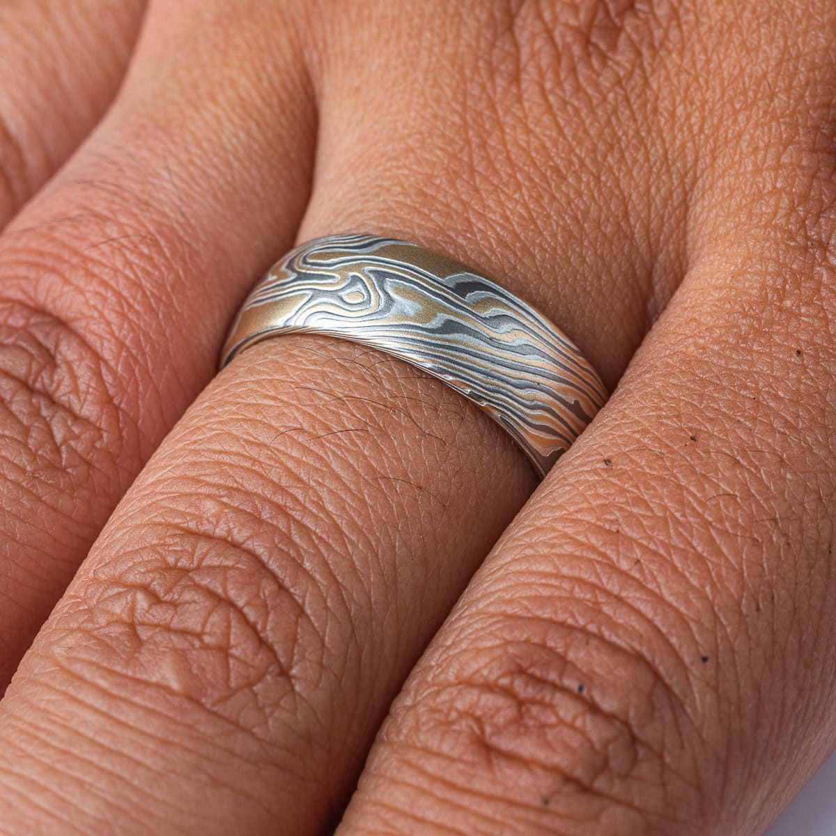 Wide men's style mokume gane ring, patterned in a Twist style, made with yellow gold, palladium and silver.