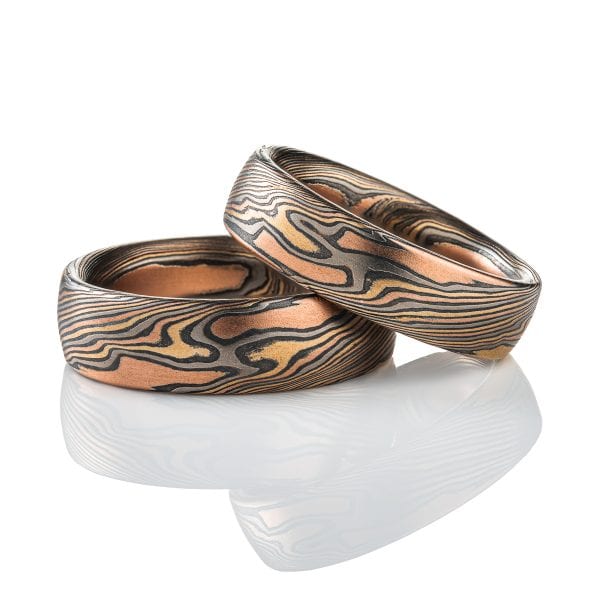 Matching set of mokume gane rings, made in twisting pattern, and both made in a combination of red gold, yellow gold, palladium and silver.