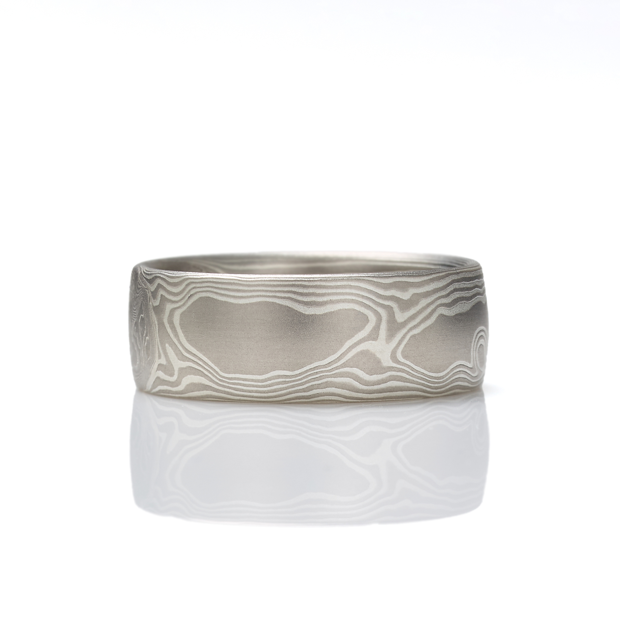 Mokume gane ring patterned in a classic woodgrain style, made with layers of palladium and silver, lightly etched for a slight texture, wide to suit a men's style, and with a low dome profile.